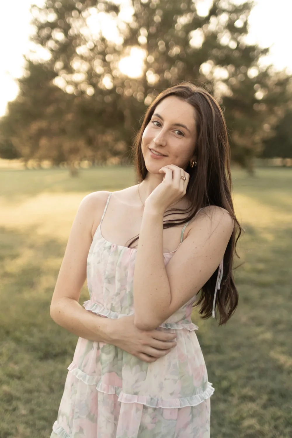 Marley, standing outdoors at golden hour in a floral dress, smiling